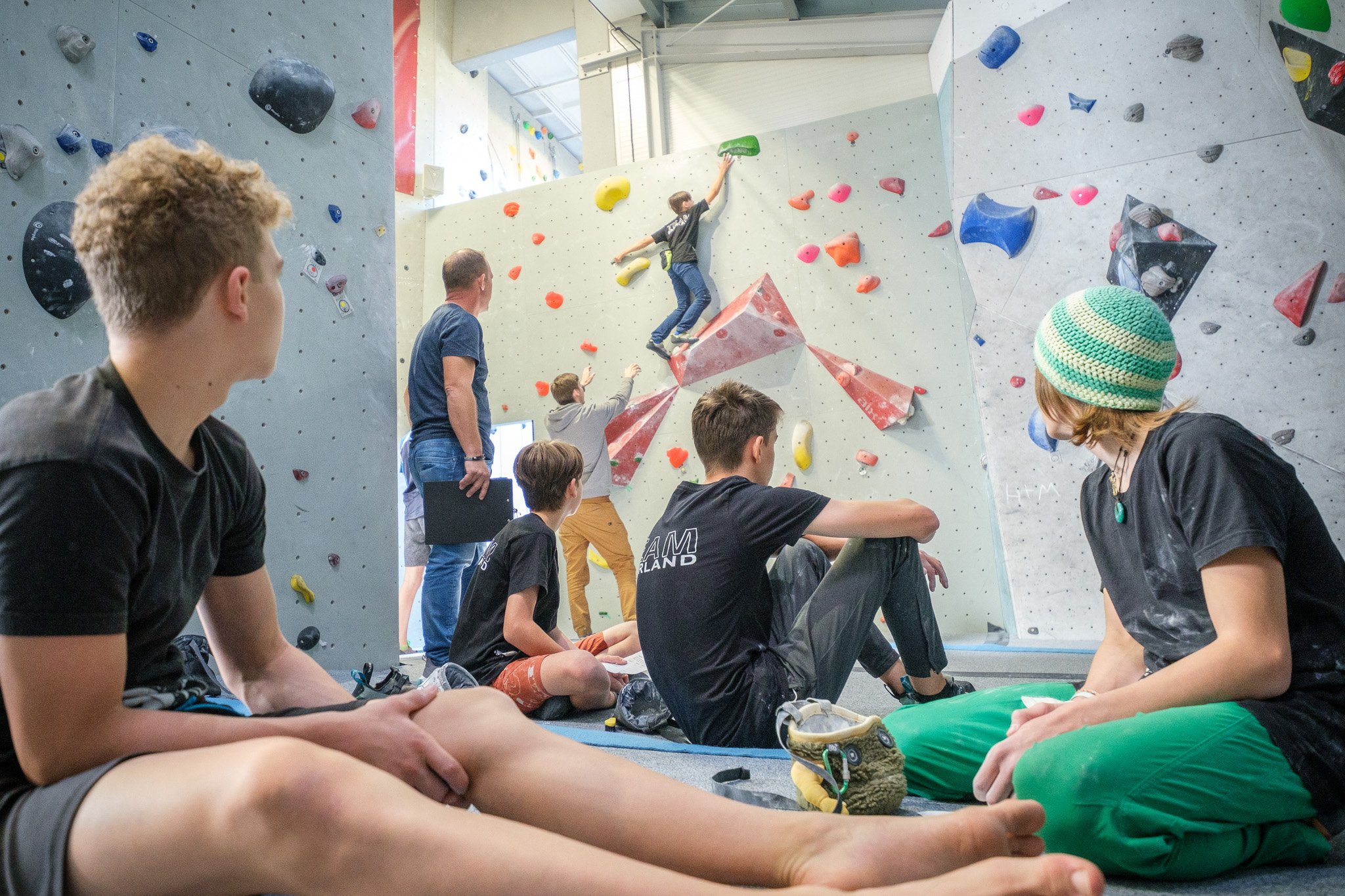 Junge Personen schauen im Rocklands Kletterzentrum beim Bouldern zu